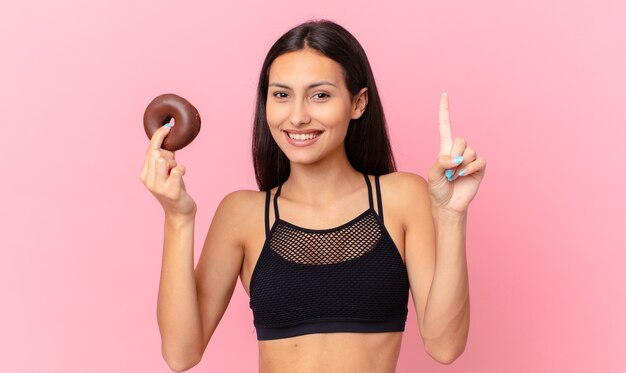 Mooie fitnessvrouw met een donut en een ontbijtkom