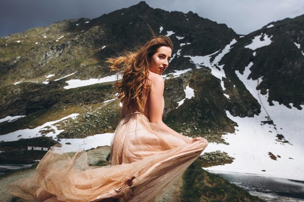 Mooie foto van een blanke vrouw in een elegante jurk die zich voordeed op sneeuwende bergen