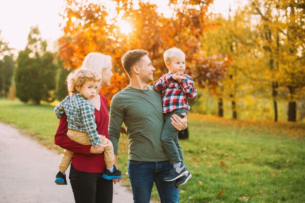 Mooie foto van jonge ouders en twee kleine bouys, wandelen in het park