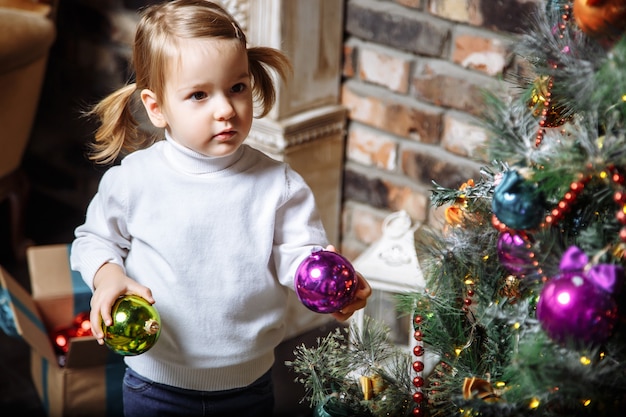 Mooie foto van schattig klein meisje kerstboom thuis versieren