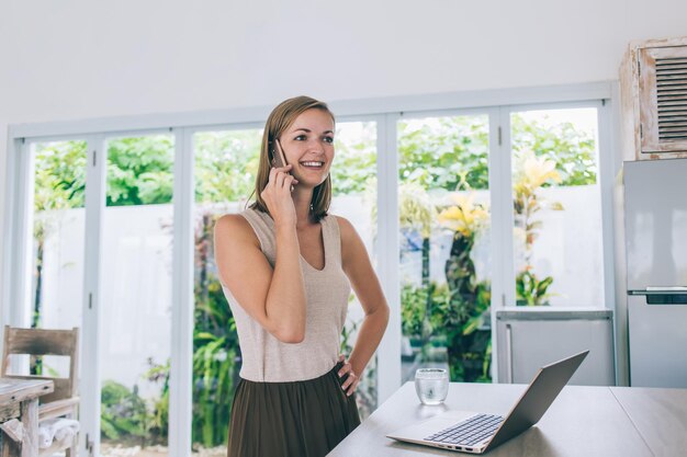 Mooie freelance vrouw praten op mobiel thuis