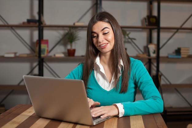 Mooie freelancer werkt met iets en zit aan de houten tafel met laptop