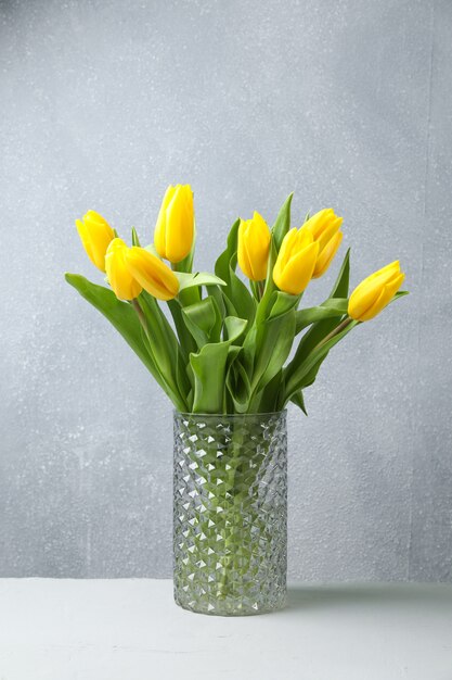 Mooie gele tulpen in een glazen vaas op houten tafel