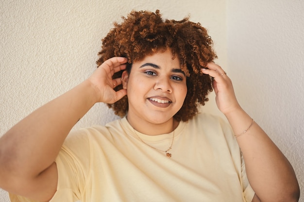 Mooie gelukkig lachende bochtige plus size Afrikaanse zwarte vrouw afro haar met make-up poseren in beige