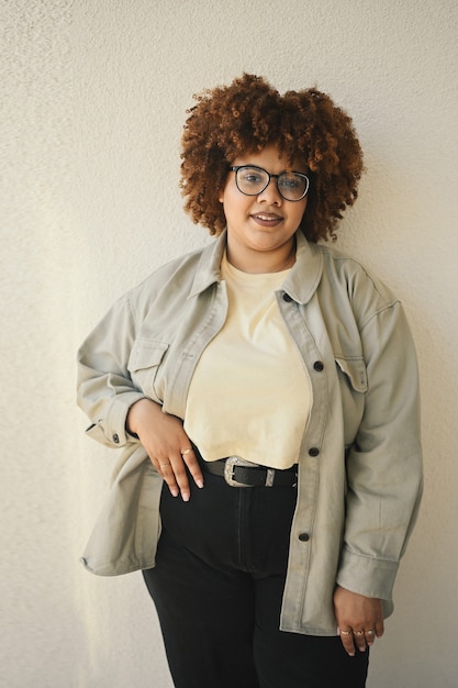 Mooie gelukkig lachende bochtige plus size Afrikaanse zwarte vrouw afro haar poseren beige tshirt jeans