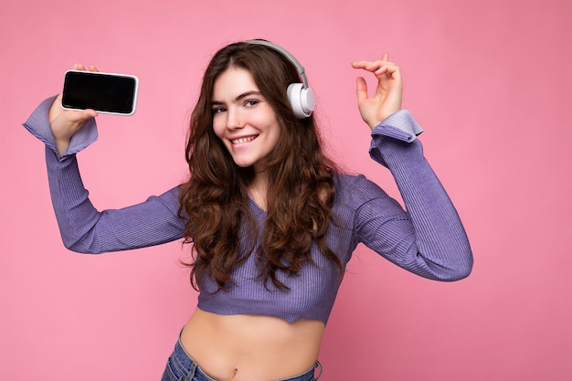 Mooie gelukkig lachende jonge vrouw draagt stijlvolle casual outfit geïsoleerd op achtergrond muur