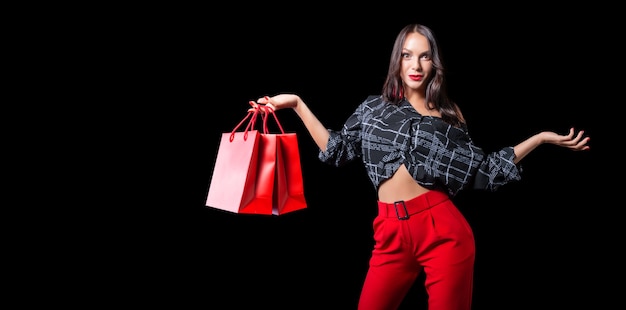 Mooie gelukkige brunette met rode pakketten in haar handen