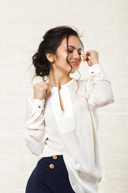 Mooie gelukkige donkerbruine vrouw in een witte blouse