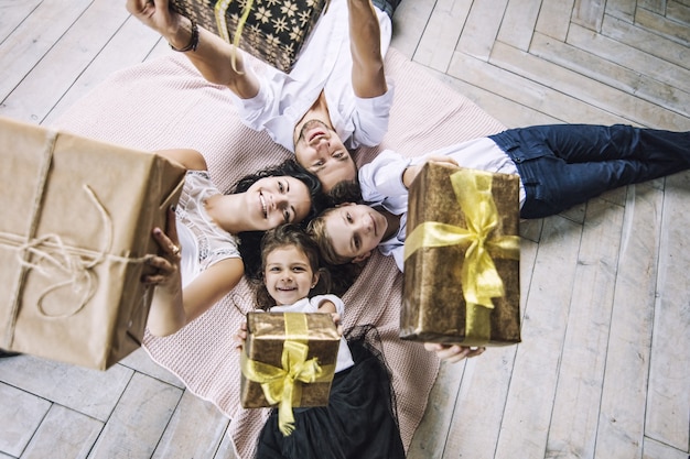 Mooie gelukkige familie moeder vader zoon en dochter met geschenken in de handen liggen op de vloer