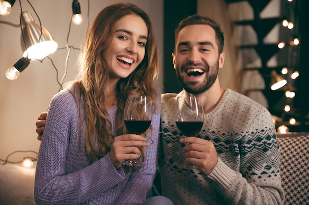 Mooie gelukkige jonge paar romantische avond samen thuis doorbrengen, rode wijn drinken, roosteren