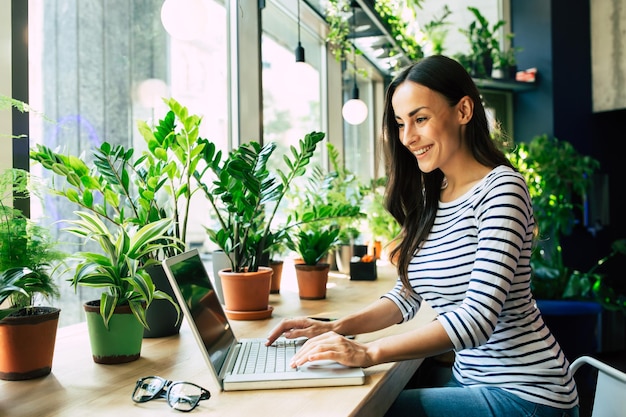 Mooie gelukkige jonge vrouw met laptop in stadscafé