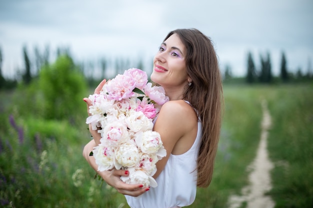 Mooie gelukkige lachende vrouw met pioenrozen meisje met een boeket bloemen