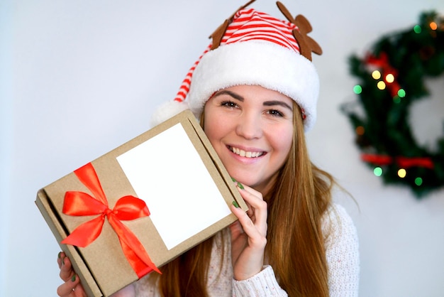 Mooie gelukkige meisjes jonge vrouw in de hoed van de kerstman met huidige doos in handen cadeau met rood