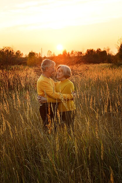 Mooie gelukkige paar knuffelen op veld tijdens zonsondergang