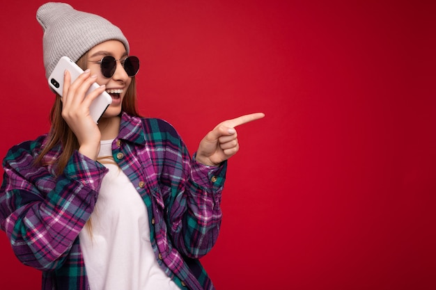 Mooie gelukkige positieve jonge blonde vrouw, gekleed in hipster paars shirt en casual wit