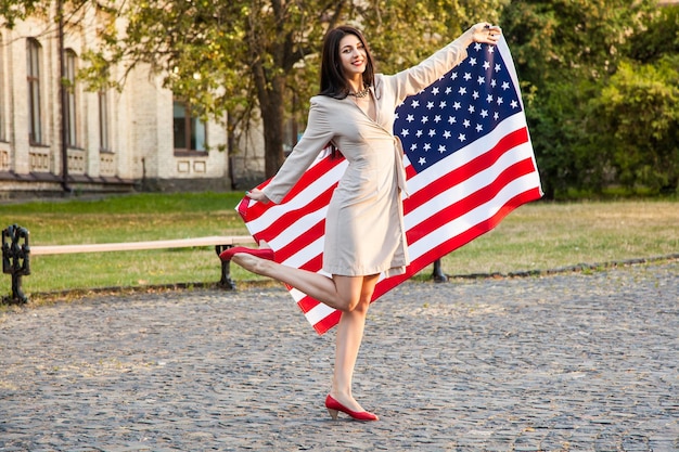 Mooie gelukkige vrouw met amerikaanse vlag die onafhankelijkheidsdag viert