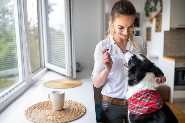 Mooie gelukkige vrouw spelen, ontspannen met haar hond thuis