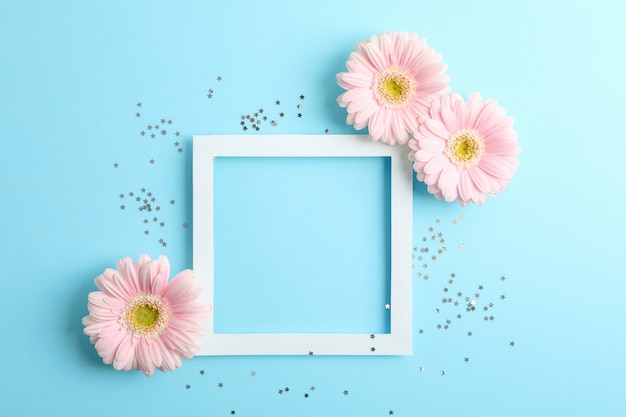 Mooie gerbera's en frame op kleur achtergrond, ruimte voor tekst