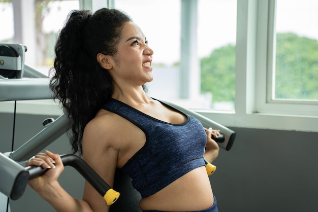 Mooie gespierde fitte vrouw die spieren traint gespierde atletische vrouwelijke bodybuilder getrokken op sportsimulator