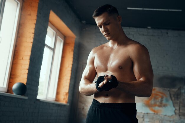 Foto mooie gespierde man die sporthandschoenen draagt terwijl hij in de sportschool staat.