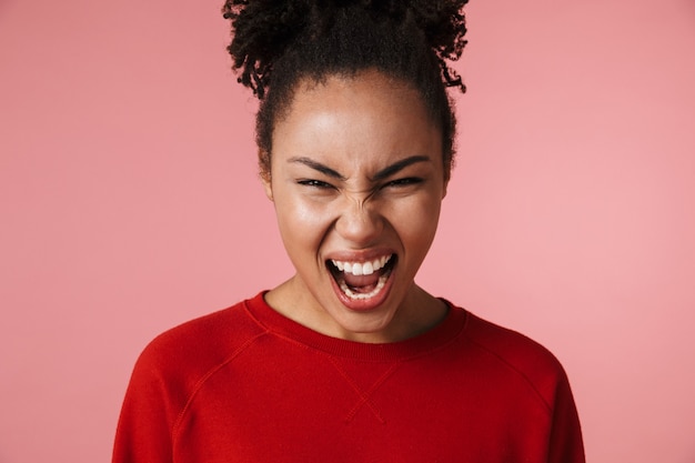 mooie geweldige schreeuwende jonge Afrikaanse vrouw poseren geïsoleerd over roze muur.