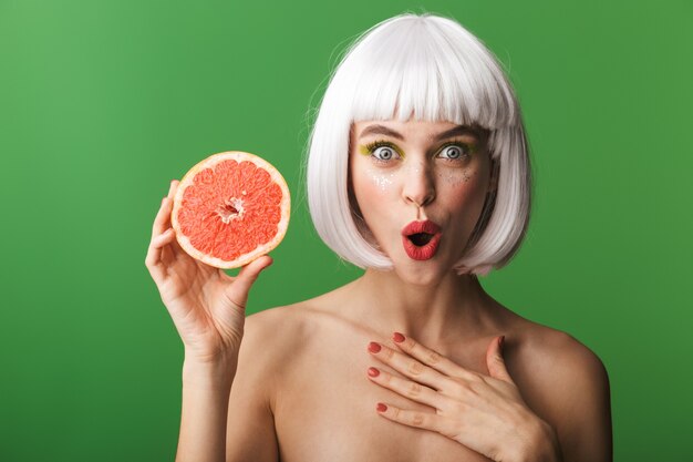 Mooie gezonde jonge topless vrouw met kort wit haar staande geïsoleerd, met gesneden grapefruit