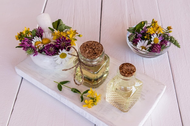 Mooie glazen flessen met natuurlijke oliën van weidegenezende planten op een wit houten podium organische zelfzorg selectieve focus