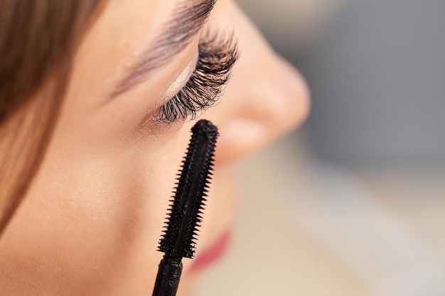 Mooie glimlach jonge vrouw die make-up doet in haar badkamer