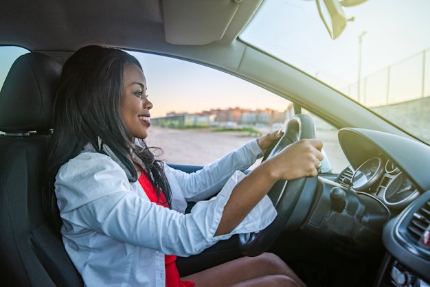 Mooie glimlachende afro-amerikaanse vrouw die een auto bestuurt