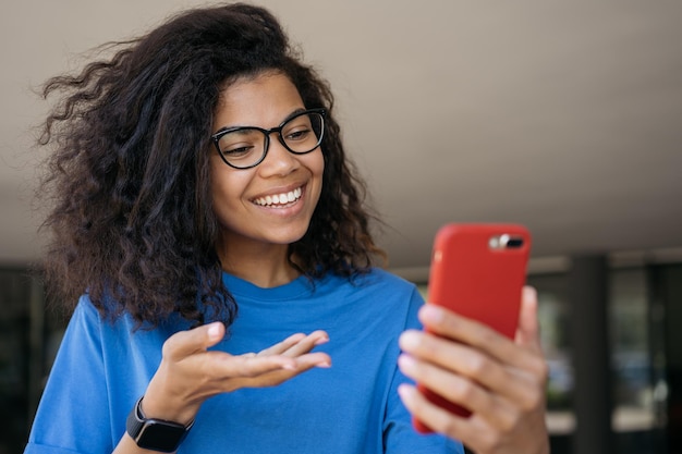 Mooie glimlachende Afro-Amerikaanse vrouw die mobiele telefooncommunicatie online gebruikt met een videogesprek