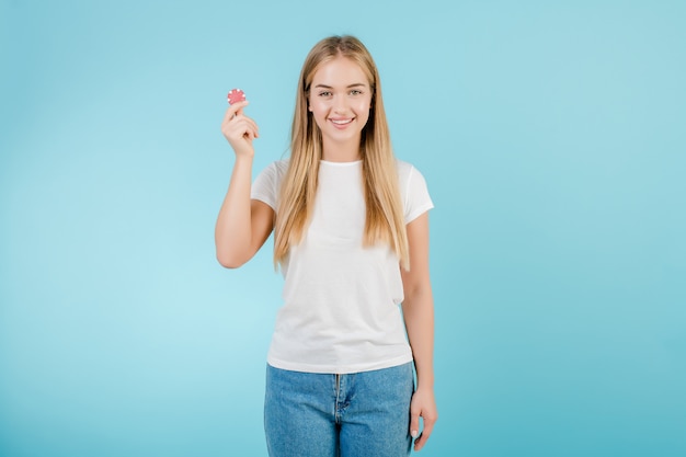 Mooie glimlachende blondevrouw met pookspaander van online casino dat over blauw wordt geïsoleerd