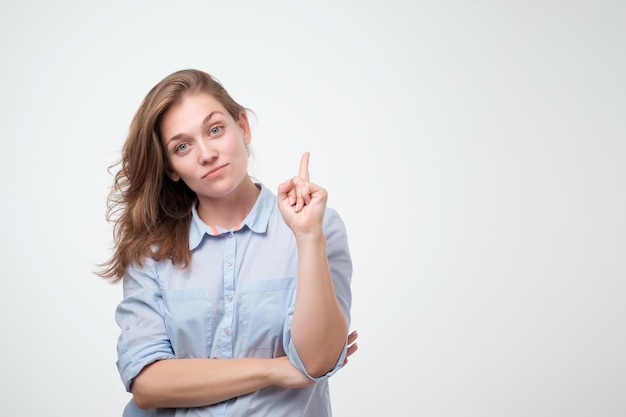 Mooie glimlachende dromende vrouw die met de wijsvinger omhoog wijst Geïsoleerd op witte achtergrond