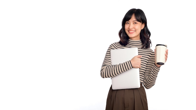 Mooie glimlachende jonge aziatische onderneemster die laptopcomputer en kop van koffie draagt om te gaan terwijl status geïsoleerd over witte achtergrond
