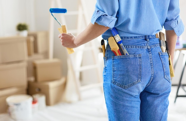 Mooie glimlachende vrouw die binnenmuur van huis schildert met verfroller