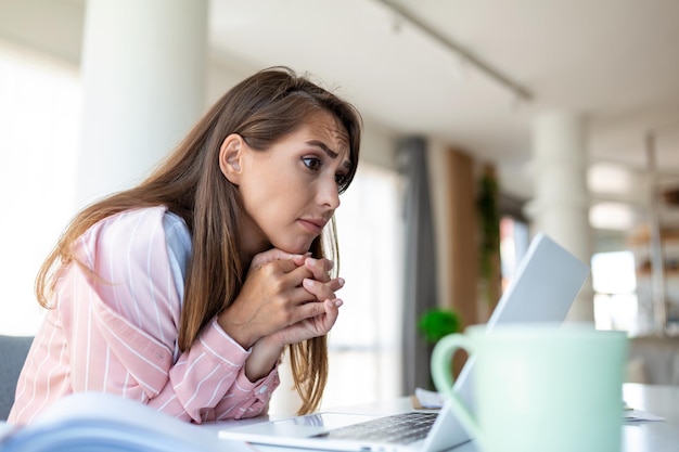 Mooie glimlachende zakenvrouw die iets op een laptop leest terwijl ze op de tafel op kantoor leunt