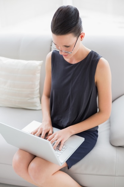 Mooie goed geklede jonge vrouw met behulp van de laptop