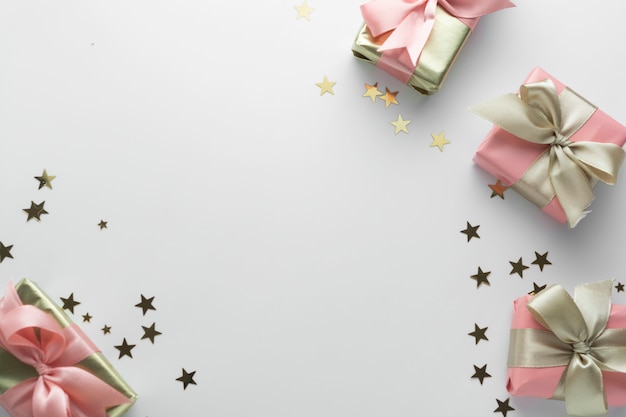 Mooie gouden geschenken glitter lint van conffeti roze bogen op wit. Kerstmis, feest, verjaardag. Vier glimmende verrassingsdozen copyspace. Creatieve plat lag bovenaanzicht.