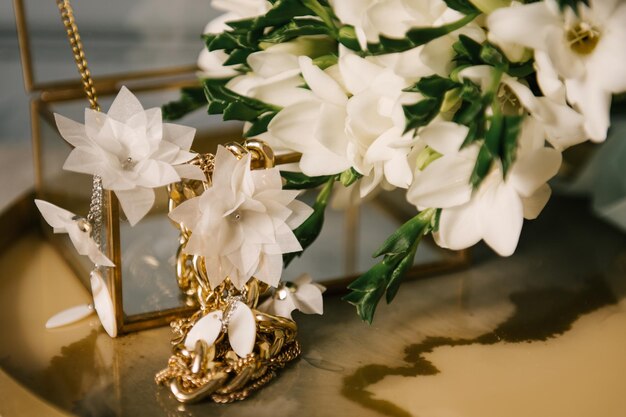 Mooie gouden oorbellen naast bloemen interieurdetails van een damesslaapkamer