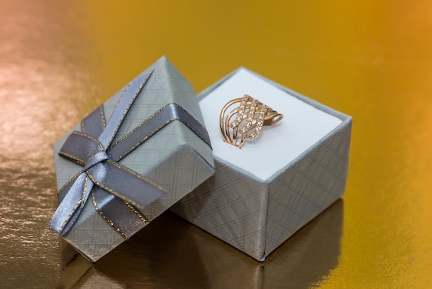 Mooie gouden sieraden in geschenkdoos op gouden achtergrond