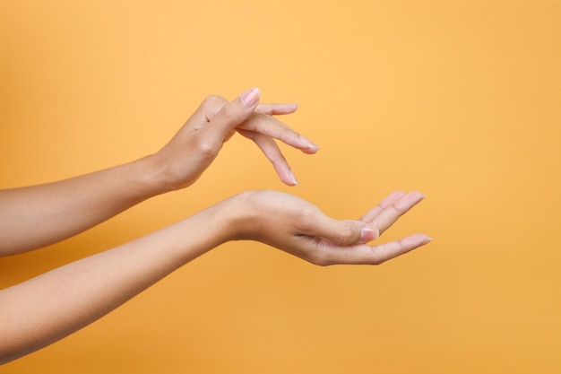 Mooie handen die massagecrème aanbrengen geïsoleerd op een gele achtergrond