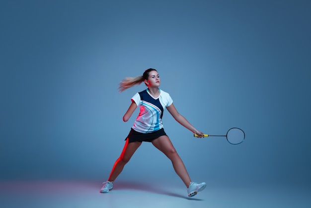 Mooie handicap vrouw beoefenen in badminton geïsoleerd op blauwe achtergrond in neonlicht