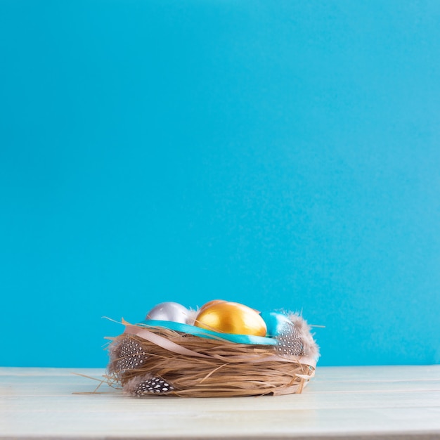 Mooie Happy Easter vakantie groet banner met Pasen nest met gekleurde eieren en versierd met linten op lichte houten achtergrond met kopie ruimte voor tekst op blauw