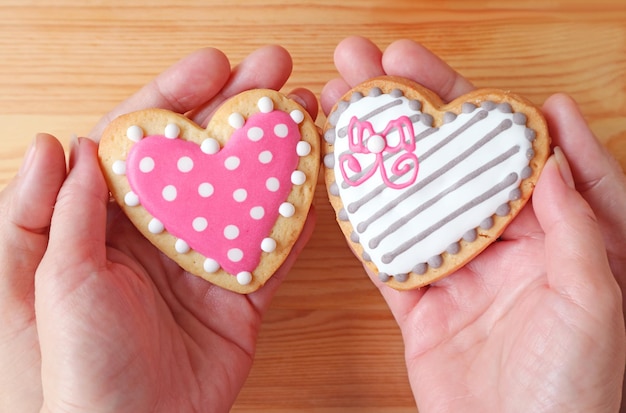 Mooie hartvormige koekjes in de handen van de vrouw met de handen van de man op houten achtergrond