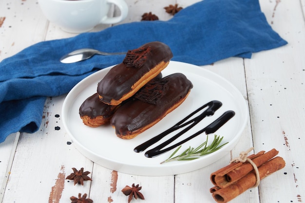 Mooie heerlijke franse eclairs set met origineel crème decor op witte plaat op houten achtergrond smakelijke kleurrijke dessert soesjes