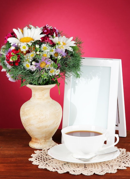 Mooie heldere bloemen in vaas op tafel op roze achtergrond