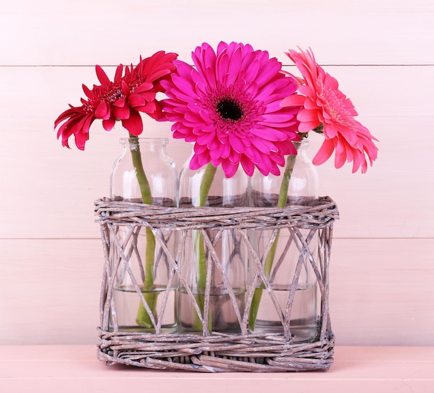 Mooie heldere gerbera's in glazen vazen op houten ondergrond