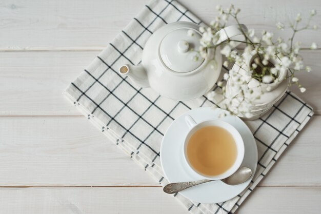 Mooie heldere theeset. Witte keramische theepotten en thee-ingrediënten, bovenop de witte tafel.