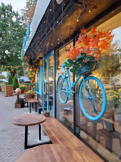 Mooie herfstcafé-buitenkant, blauwe fiets, geeloranje bladeren