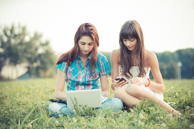 mooie hipster jonge vrouwen zusters vrienden met behulp van tablet en smartphone