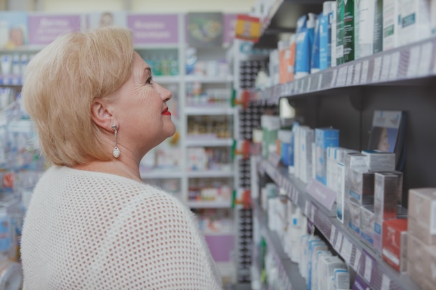 Mooie hogere vrouw die bij drogisterij winkelt